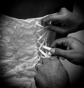 Mani del sarto sul vestito della sposa